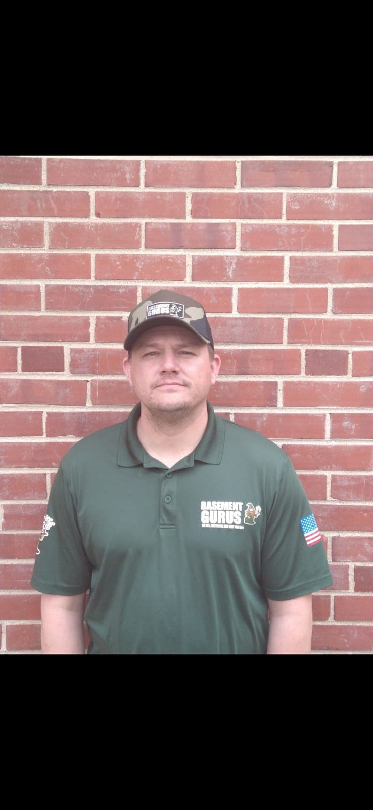 A Basement Gurus team member in a company polo outside the shop.