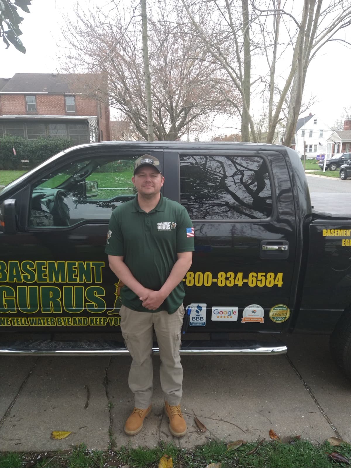 A Basement Gurus technician standing beside a wrapped company truck.